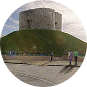 View of Clifford's Tower. The tower sits on top of a large grassy mound. 